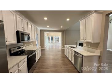 Open-concept kitchen with white cabinets, stainless steel appliances, and seamless flow into the living area at 8703 Ellington Park Dr, Charlotte, NC 28277