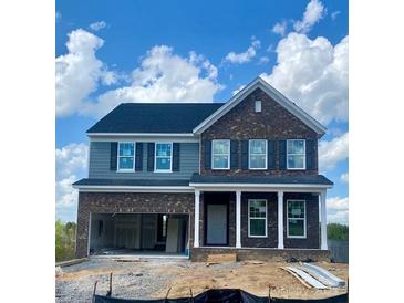 Two-story home featuring a brick facade, gray siding, a two-car garage, and a covered front porch, all under a blue sky at 13705 Roderick Dr # 194, Huntersville, NC 28078