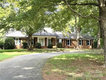 Charming brick home with lush trees, a curved driveway, and a welcoming front porch at 4210 Wrangler Sw Dr, Concord, NC 28027