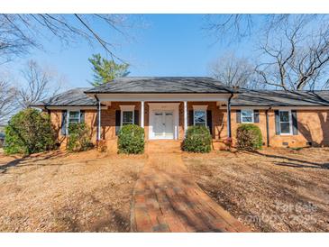 Charming brick home with inviting front porch and well-manicured landscaping at 4210 Wrangler Sw Dr, Concord, NC 28027