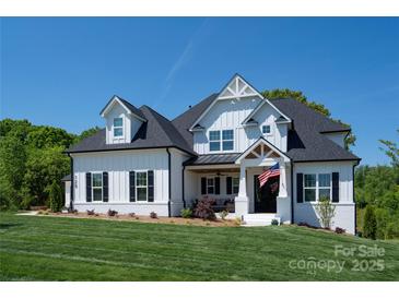 Beautiful white farmhouse with black shutters and an American flag waving in the breeze. Perfectly manicured lawn at 129 Ryleigh Dan Pl, Mooresville, NC 28115