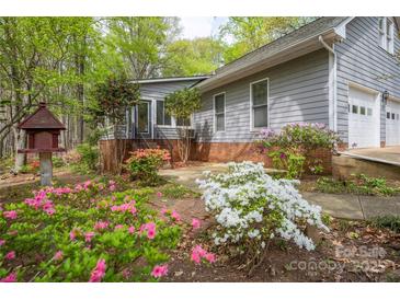 Charming home exterior with gray siding, brick foundation, and colorful flowering shrubbery at 140 Rustic Way Ln, Mooresville, NC 28117