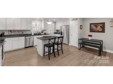 Well-lit kitchen boasts stainless steel appliances, white cabinets, and a breakfast bar with granite countertops at 3041 Mulberry Ln, Lancaster, SC 29720