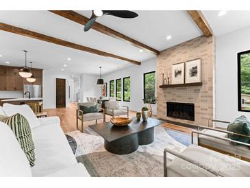 Bright living room with wood beam ceiling, brick fireplace, hardwood floors, and comfortable seating at 5610 Farmbrook Dr, Charlotte, NC 28210