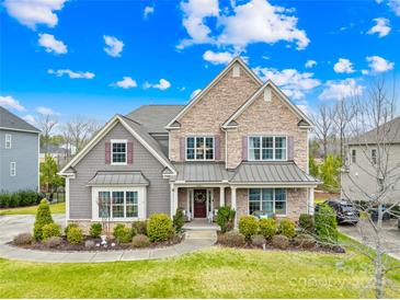 Inviting two-story home boasts a manicured lawn, stone accents, and charming curb appeal under a bright, cloudy sky at 6022 Candlestick Ln, Lancaster, SC 29720