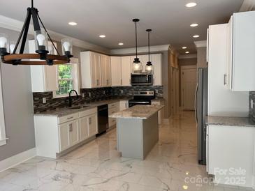 Bright kitchen with white cabinets, an island, stainless appliances, and elegant marble floors at 7221 Static Way # 13, Sherrills Ford, NC 28673