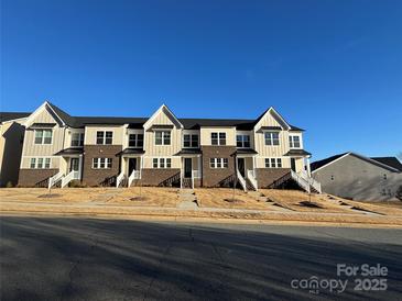 Charming townhome exterior featuring brick accents, neutral siding and individual front entryways with a shared green space at 108 Glencoe Ln # 105, Mooresville, NC 28117