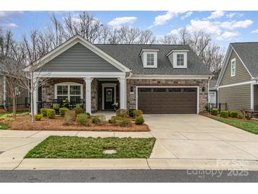 Charming single-story home featuring stone and gray siding, well-manicured landscaping, and a two-car garage at 15103 Honeycutt Dr, Huntersville, NC 28078