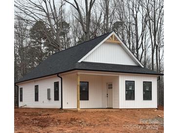 Charming white home with black roof, siding, and dark framed windows, surrounded by bare trees at 635 Academy St, Cleveland, NC 27013