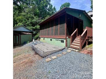 Backyard view showcasing a cozy screened-in porch, rock landscaping, and a storage shed at 152 Muskhogean Way, Mount Gilead, NC 27306
