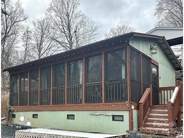 A screened porch with a brown wood frame is attached to a home with green siding and a gray sky above at 152 Muskhogean Way, Mount Gilead, NC 27306