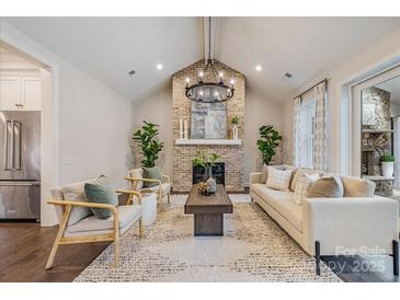 Inviting living room featuring a brick fireplace, vaulted ceiling, modern chandelier, and neutral decor at 3288 Sherman Dr, Lancaster, SC 29720