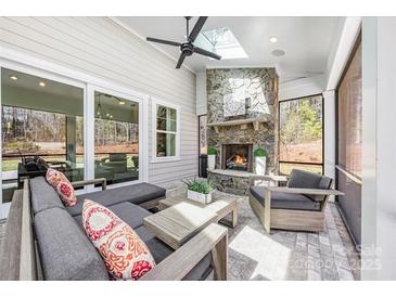 Covered patio with a stone fireplace, ceiling fan, and comfortable seating, perfect for outdoor relaxation at 3288 Sherman Dr, Lancaster, SC 29720