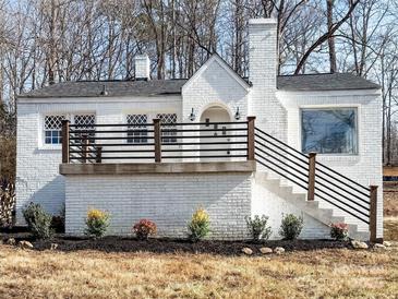 Charming white brick home featuring a cozy front porch, decorative windows and manicured landscaping at 32884 Old Salisbury Rd, Albemarle, NC 28001