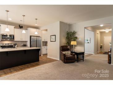 Open living space connecting to the kitchen with a comfortable recliner and view of hallway at 3156 Pinehills Way, Mount Holly, NC 28120