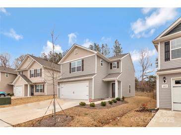 Charming two-story home featuring a two-car garage, light gray siding, and a manicured front yard with young landscaping at 561 Hawley St, Charlotte, NC 28214