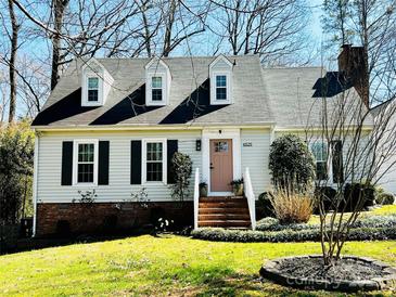 Charming home with a well-manicured lawn, brick foundation, dormer windows, and a welcoming pink front door at 6525 Castlegate Dr, Charlotte, NC 28226