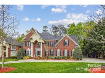 Stately brick home with manicured lawn and mature landscaping, and traditional architectural details at 12011 Olden Ct, Charlotte, NC 28262