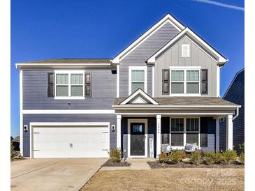 Charming two-story home features a blend of gray and blue siding, complemented by black shutters and a welcoming front porch at 1444 Harleston St, Indian Trail, NC 28079