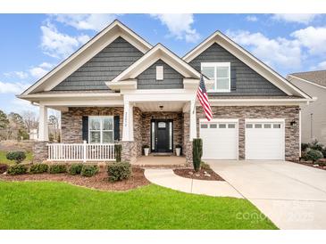 Beautiful stone home with white trim, manicured lawn, two-car garage, and covered front porch at 22030 Molly Harper Dr, Cornelius, NC 28031