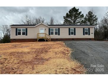 Tan home with black shutters, a small porch, and a freshly graveled driveway at 252 Fairchase Cir # 56, Stony Point, NC 28678