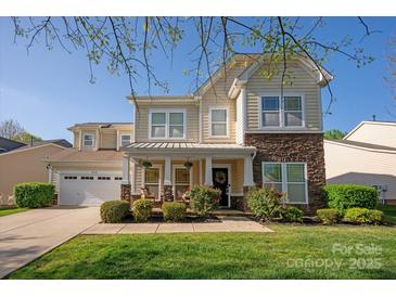 Charming two-story home with stone accents, covered porch, manicured lawn, and attached two car garage at 3216 Bridgewick Rd, Waxhaw, NC 28173