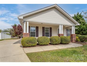 Charming home featuring a covered front porch and well-maintained landscaping with manicured shrubbery at 406 Llewellyn St, Belmont, NC 28012