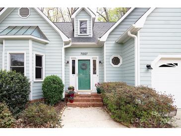 Charming home showcasing a quaint entrance, complemented by lush landscaping and a welcoming front door at 7007 Chapparall Ln, Charlotte, NC 28215