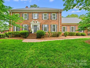Charming brick home features lush landscaping, a well-manicured lawn, gray shutters, and an elegant entrance at 7329 Kennington Ct, Charlotte, NC 28270