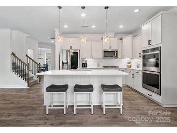 Modern kitchen with a central island, sleek white cabinetry, stainless steel appliances and stylish pendant lights at 3038 Lydney Cir, Waxhaw, NC 28173