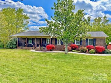 Charming brick home with a lush green lawn, vibrant landscaping, and a welcoming front porch at 4866 E Nc Hwy 150 Hwy, Lincolnton, NC 28092