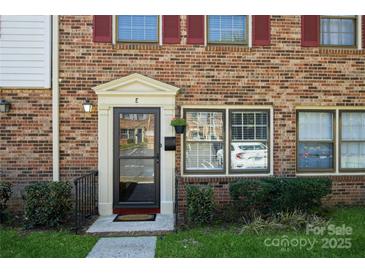 Charming brick townhome with red shutters, well-maintained landscaping, and inviting front entrance at 6322 Old Pineville Rd # E, Charlotte, NC 28217