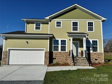 Two story home with a green exterior, stone accents, two car garage, and front porch at 1022 Heath Helms Rd, Monroe, NC 28110