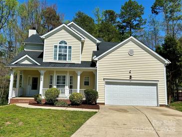 Charming home featuring a well-manicured lawn, cozy front porch, and an attached two-car garage at 10550 Worsley Ln, Charlotte, NC 28269
