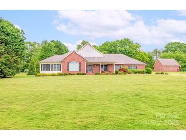Lovely brick home boasts a sprawling lawn, manicured landscaping, and charming curb appeal at 119 Era St, Troutman, NC 28166