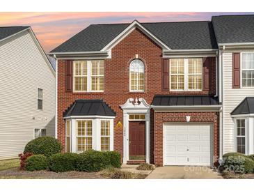 Charming brick two-story townhome with red shutters, black roof and an attached white one-car garage at 3822 Carl Parmer Dr, Harrisburg, NC 28075