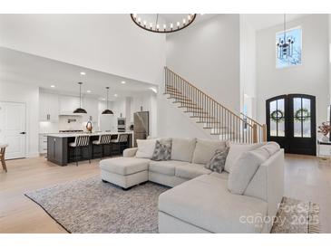 Bright, open-concept living room featuring a large sofa, a staircase, and a view into a modern kitchen at 296 Riley Dr, Taylorsville, NC 28681