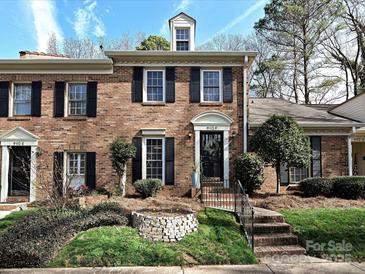 Brick townhome featuring black shutters, manicured lawn, and front steps leading to covered entryway at 9112 Nolley Ct # F, Charlotte, NC 28270