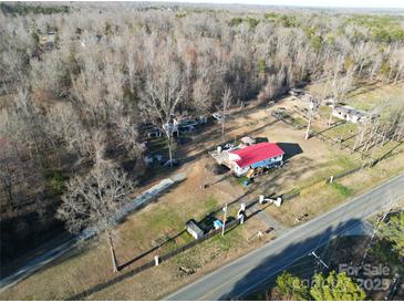 An aerial view of a home with a red roof, surrounded by trees and a large yard, near a road at 1216 Brief W Rd, Indian Trail, NC 28079