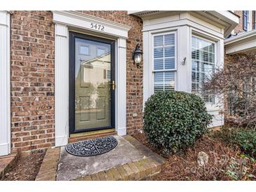 Inviting front door of a brick home with decorative door surround, transom, and meticulously maintained landscaping at 5472 Ives Nw St, Concord, NC 28027