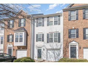 Charming townhome featuring a mix of brick and white siding, gray shutters, attached garage and manicured front yard at 932 Tiger Ln, Charlotte, NC 28262