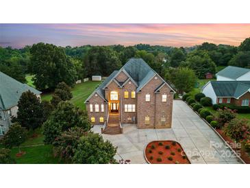 Majestic brick home with a grand entrance, manicured landscaping, and ample parking at twilight at 109 Dabbling Duck Cir, Mooresville, NC 28117