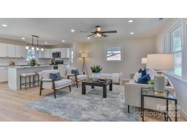 Bright living room open to a modern white kitchen with a large island and bar seating at 3617 12Th Street Ne Dr, Hickory, NC 28601