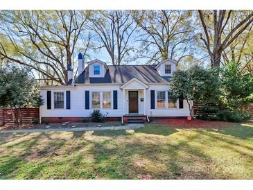 Charming cottage-style home featuring white siding, black shutters, dormer windows and a landscaped front yard at 1101 Lancaster Ave, Monroe, NC 28112