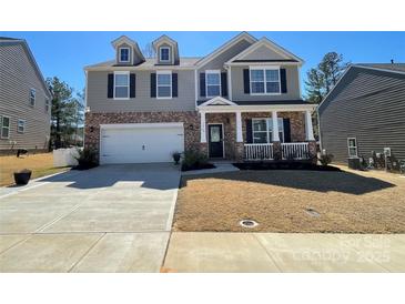 Charming two-story home with a brick and siding exterior, front porch, and a two-car garage at 121 Edgehill Ct, Troutman, NC 28166
