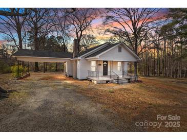 Charming cottage-style home with a covered carport and inviting front porch, surrounded by mature trees at 1216 Innis Ave, Kannapolis, NC 28081