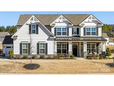 Charming two-story home featuring a welcoming front porch with stone accents and a well-manicured lawn at 702 Yucatan Dr, Waxhaw, NC 28173