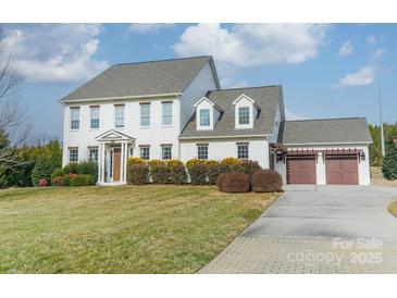 Charming white two-story home with attached garage and well-manicured lawn on a sunny day at 2027 Gloucester St, Matthews, NC 28104
