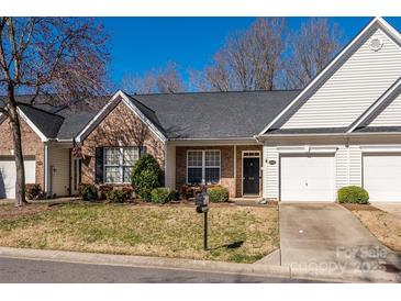 Charming brick and siding townhome with attached garage, neat landscaping, and a well-maintained lawn on a sunny day at 4642 Willow Glen Rd, Harrisburg, NC 28075