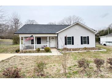 Charming single-story home featuring a cozy front porch with an American flag and a well-manicured front yard at 601 Apple St, Gastonia, NC 28054